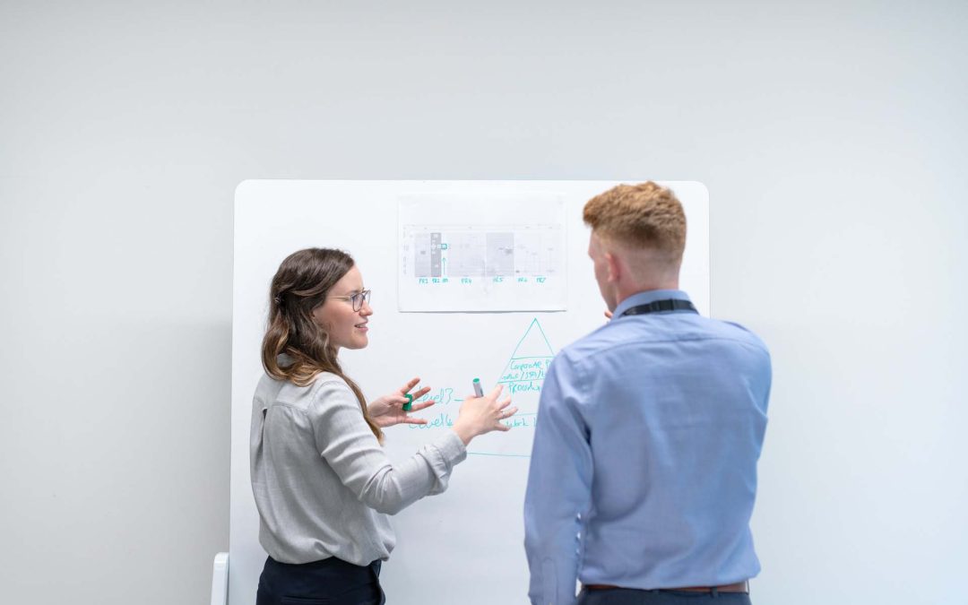 Two professionals around whiteboard constructing digital product roadmap