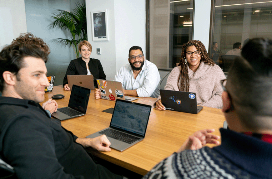 Six young professionals gathering in a boardroom to review findings of the quality assurance analyst