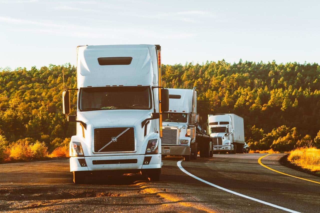 Trucking fleet pulling over to side of road near sunset. 