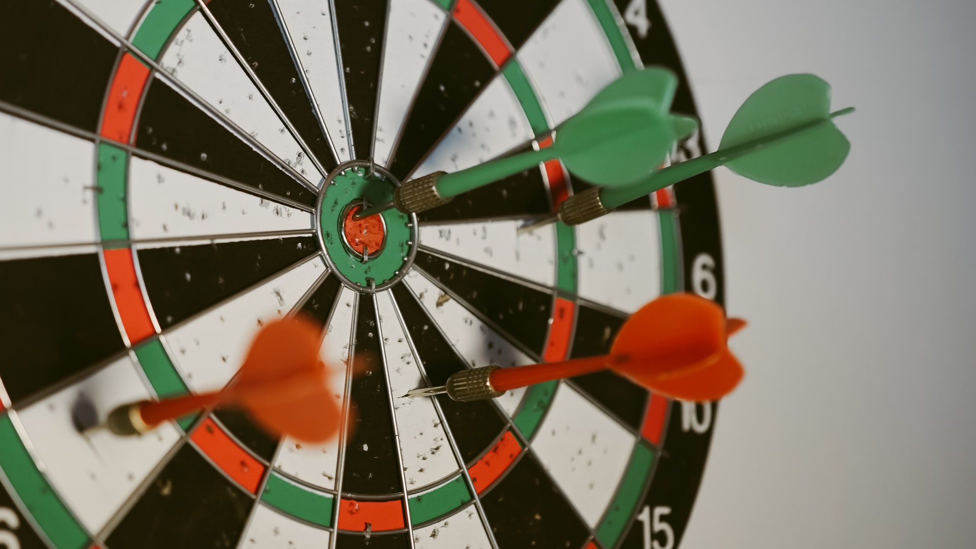 Green arrowing hitting bull's eye on a dart board