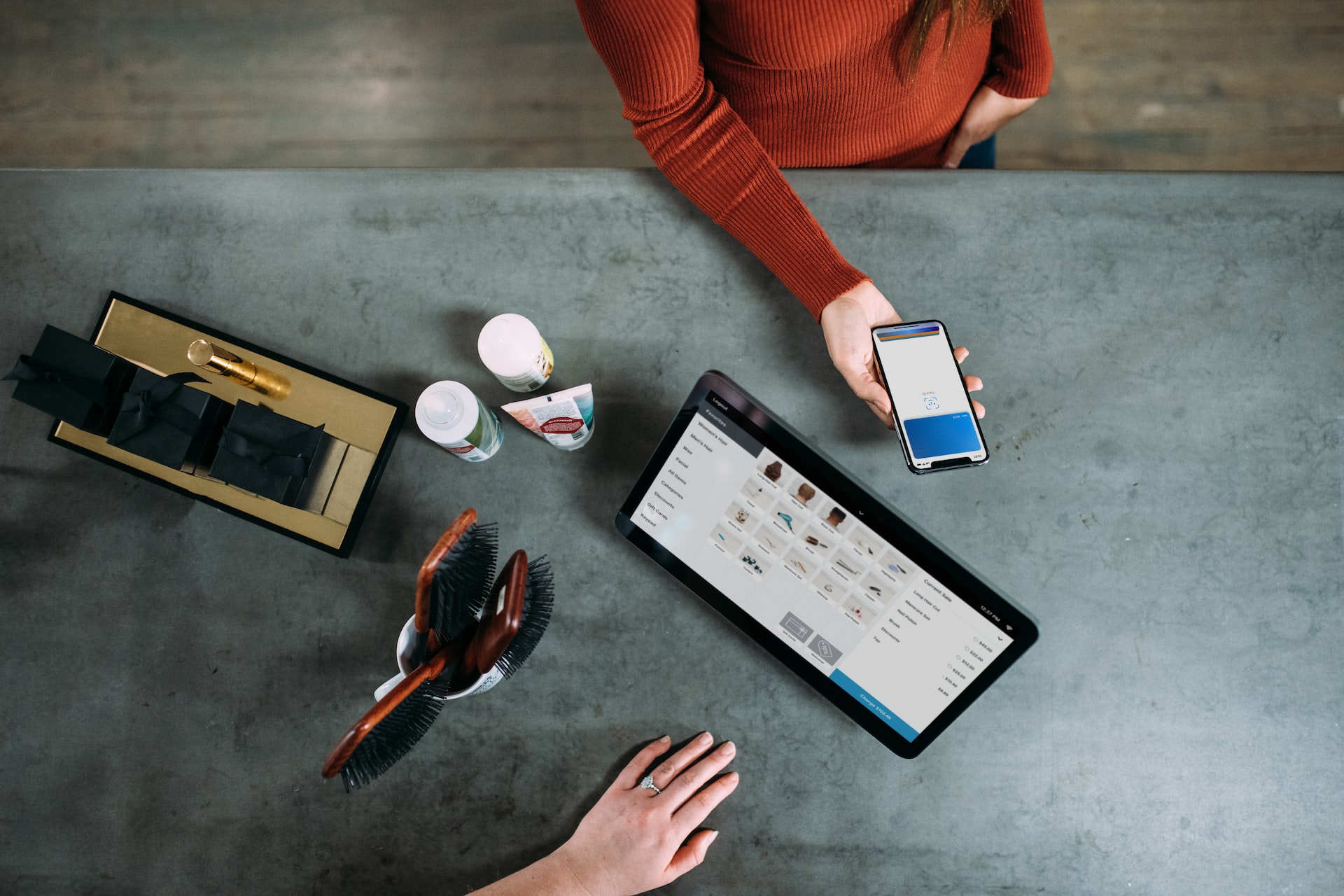 Woman in red sweater using modernized customer portal to pay for hair products at a store.