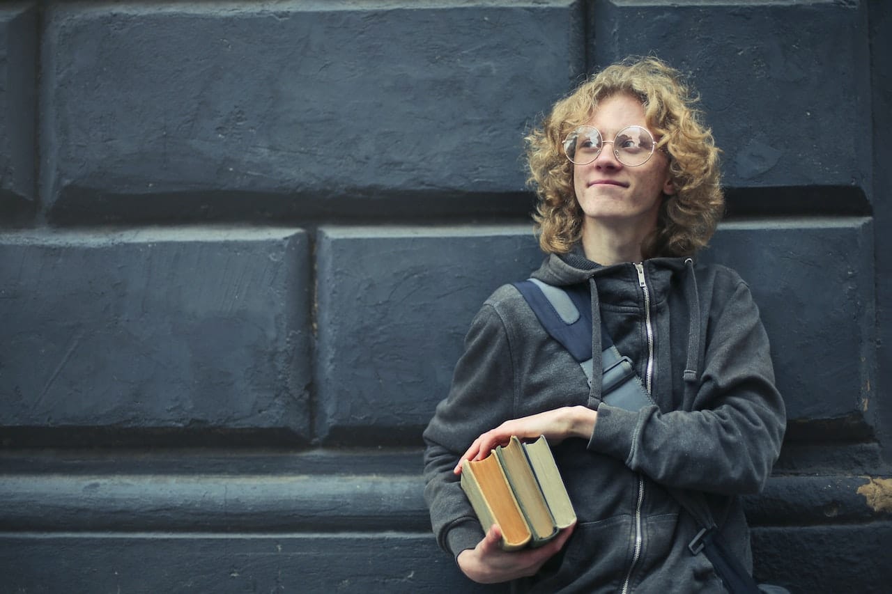 Illustration of application modernization case study: College student with long, curly blonde hair holding three books, wearing grey hoodie and with backpack