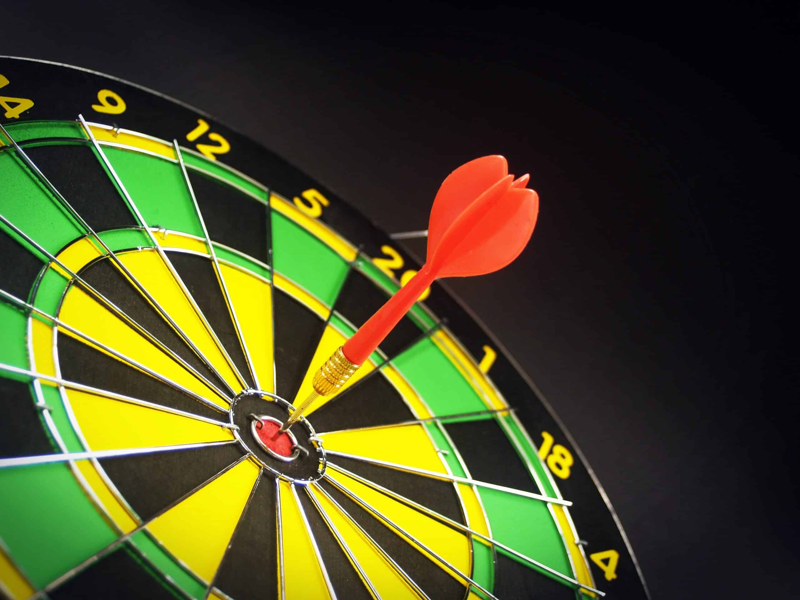 Arrow hitting the bulls-eye on a yellow and green dart board