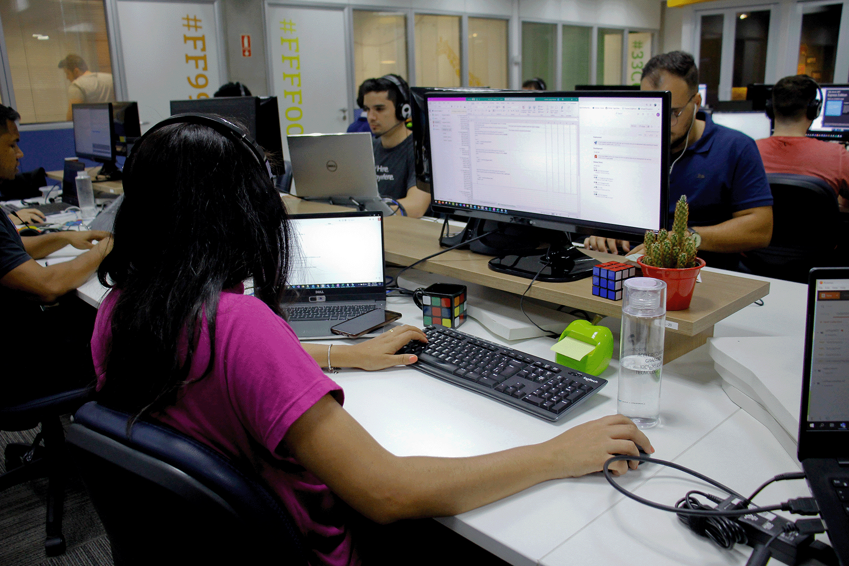 Young male and female workers checking data in office with laptops and monitor screens