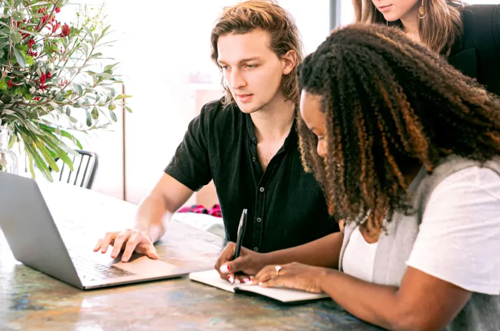 Three young professionals looking over data on a laptop. 