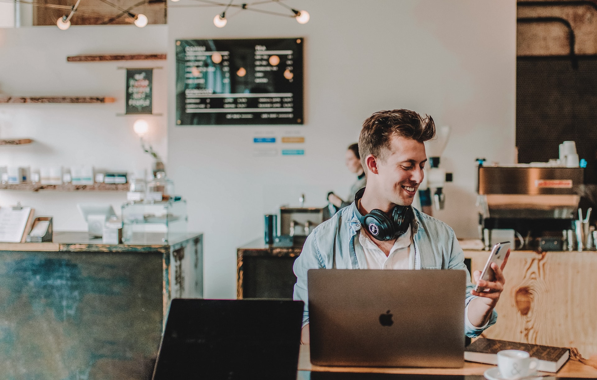 Male remote worker looking away from laptop to enjoy application on his phone