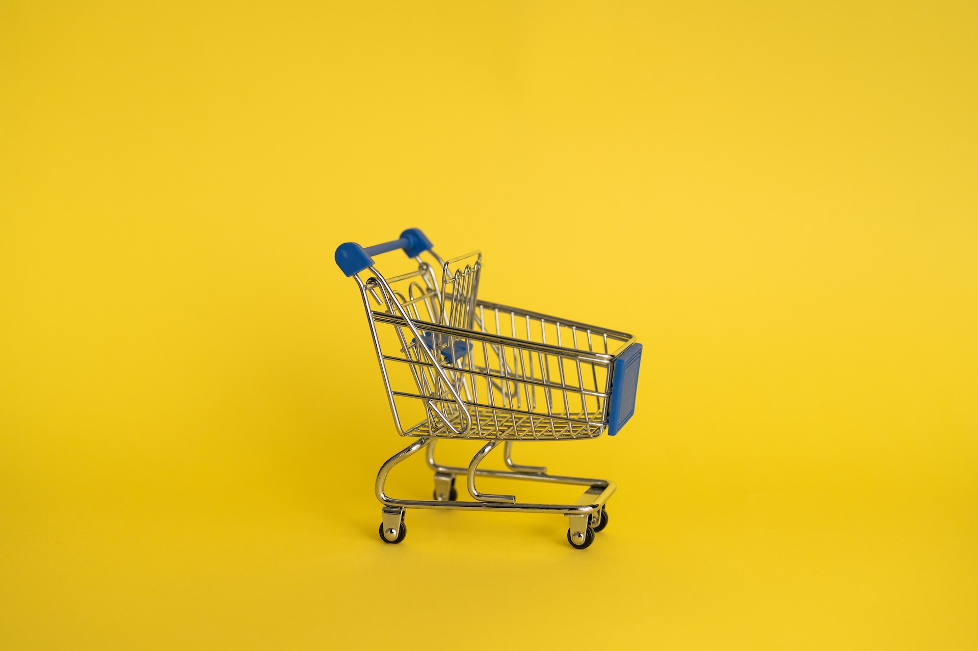 Small shopping cart in front of yellow background