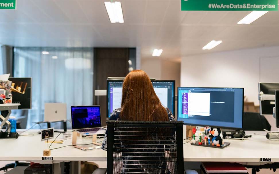 Developer at desk working on a digital product on her desktop computer