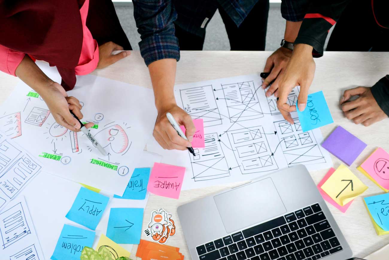 Three professionals around a boardroom planning out a digital product development process