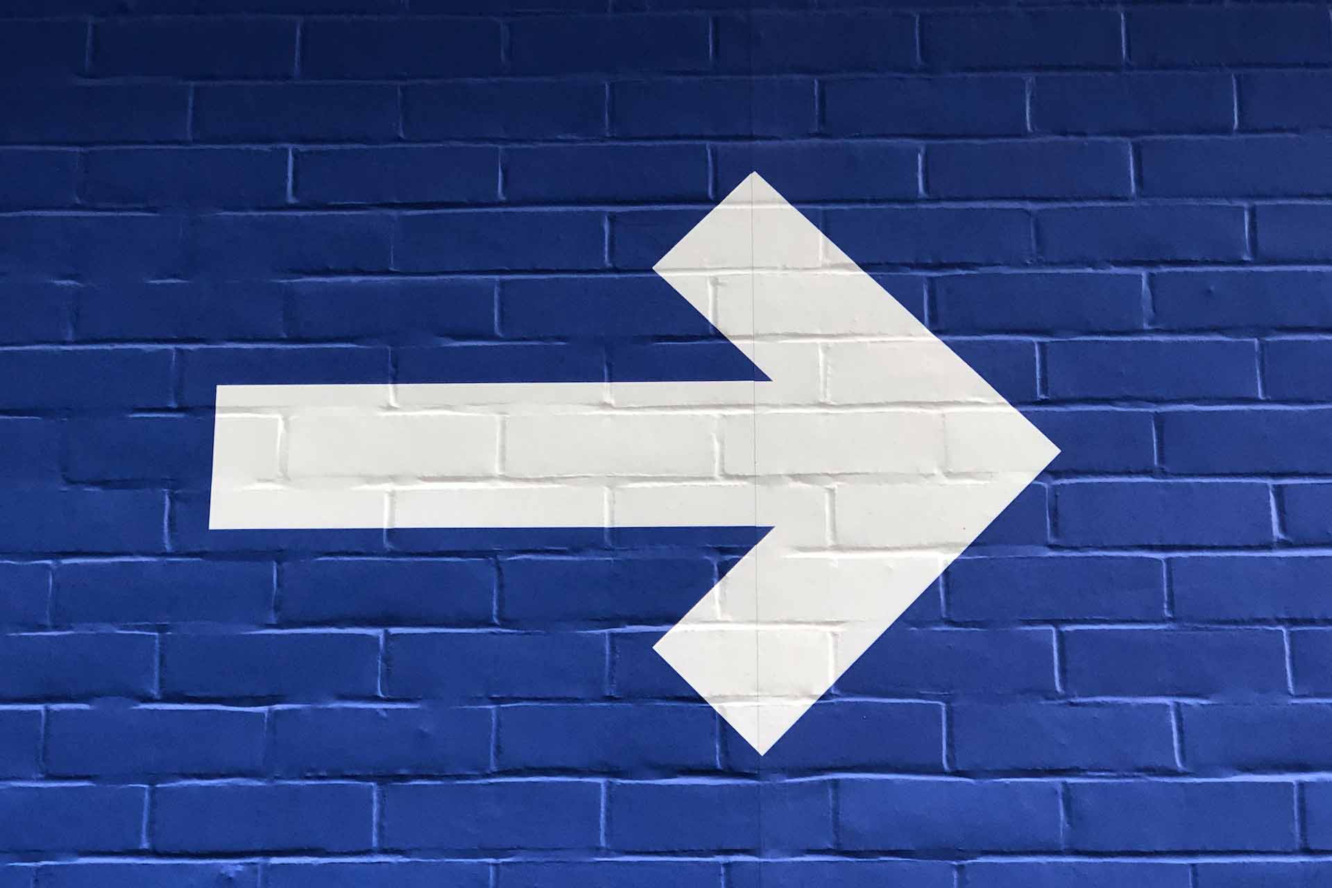 White arrow against a blue background, symbolizing application modernization trends moving businesses forward