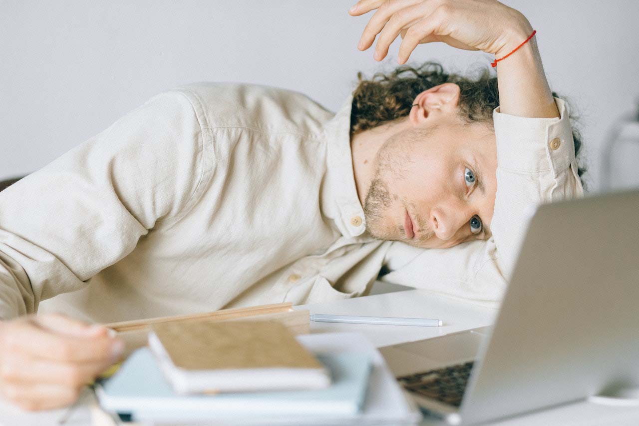 Young professional laying his arm and head on his desk, tired from change fatigue