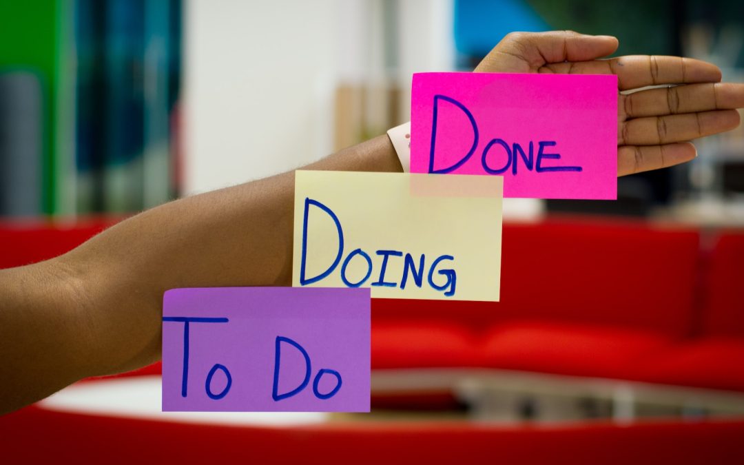 Professional holding up notes reading “to do,” “doing,” “done,” representing the velocity of completing tasks in agile digital product development