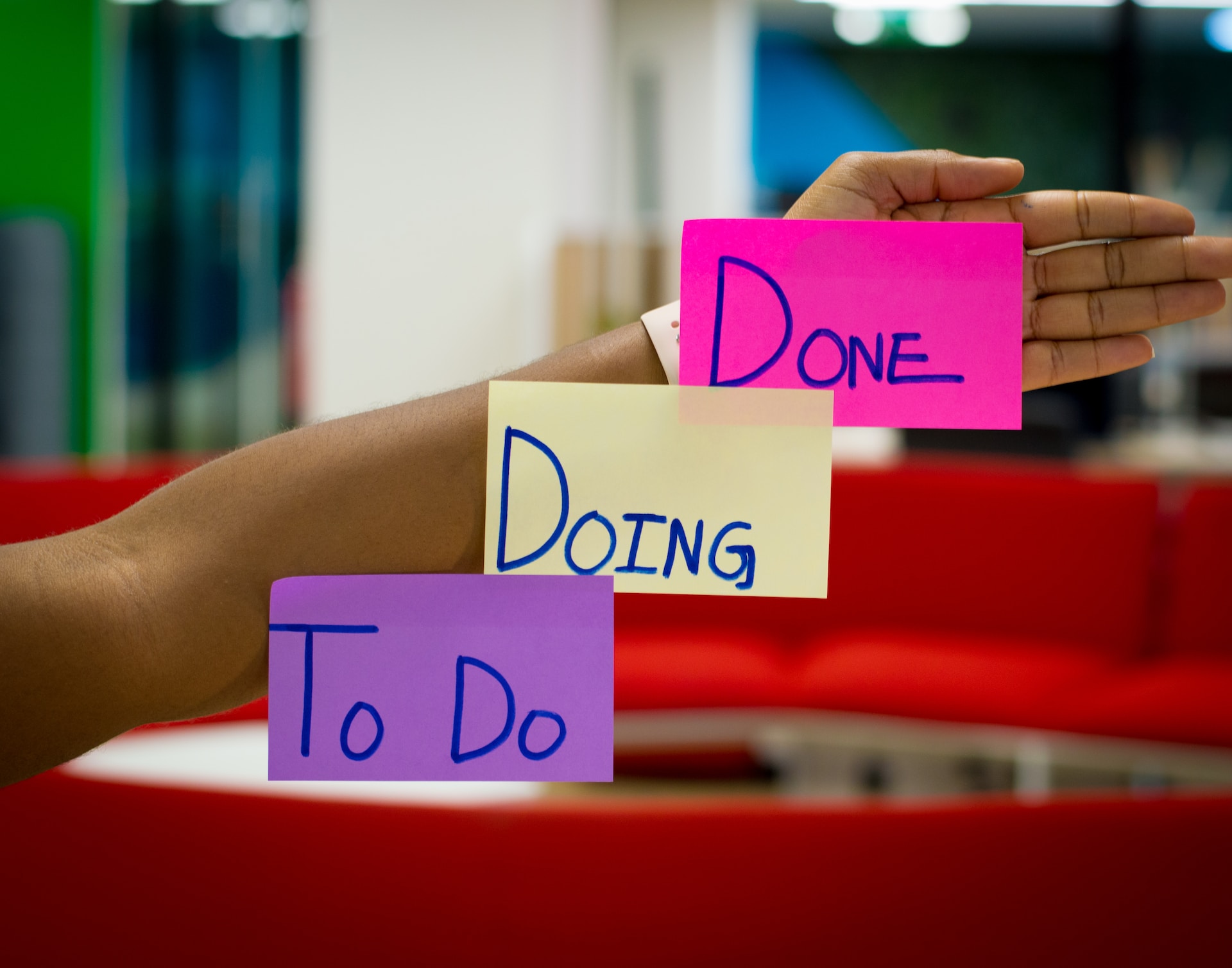Professional holding up notes reading “to do,” “doing,” “done,” representing the velocity of completing tasks in agile digital product development