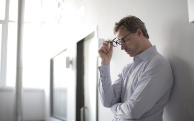 Executive standing against a white wall with glasses in hand, frustrated with progress of digital maturity