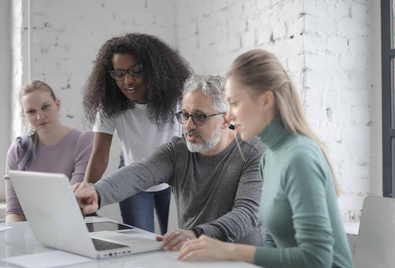 Team of professionals gathered around a laptop reviewing latest digital maturity initiative