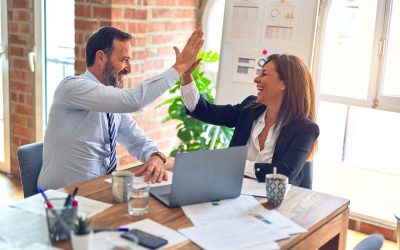 Two business executives high-fiving at desk after successful application modernization initiative