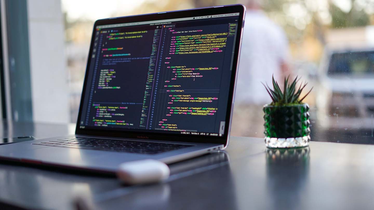 Laptop on table displaying code written by programmer