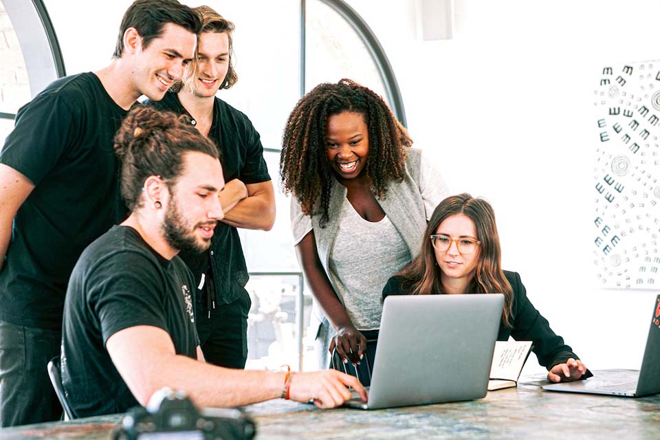 Team of young professionals gathered around laptop reviewing modernized legacy application