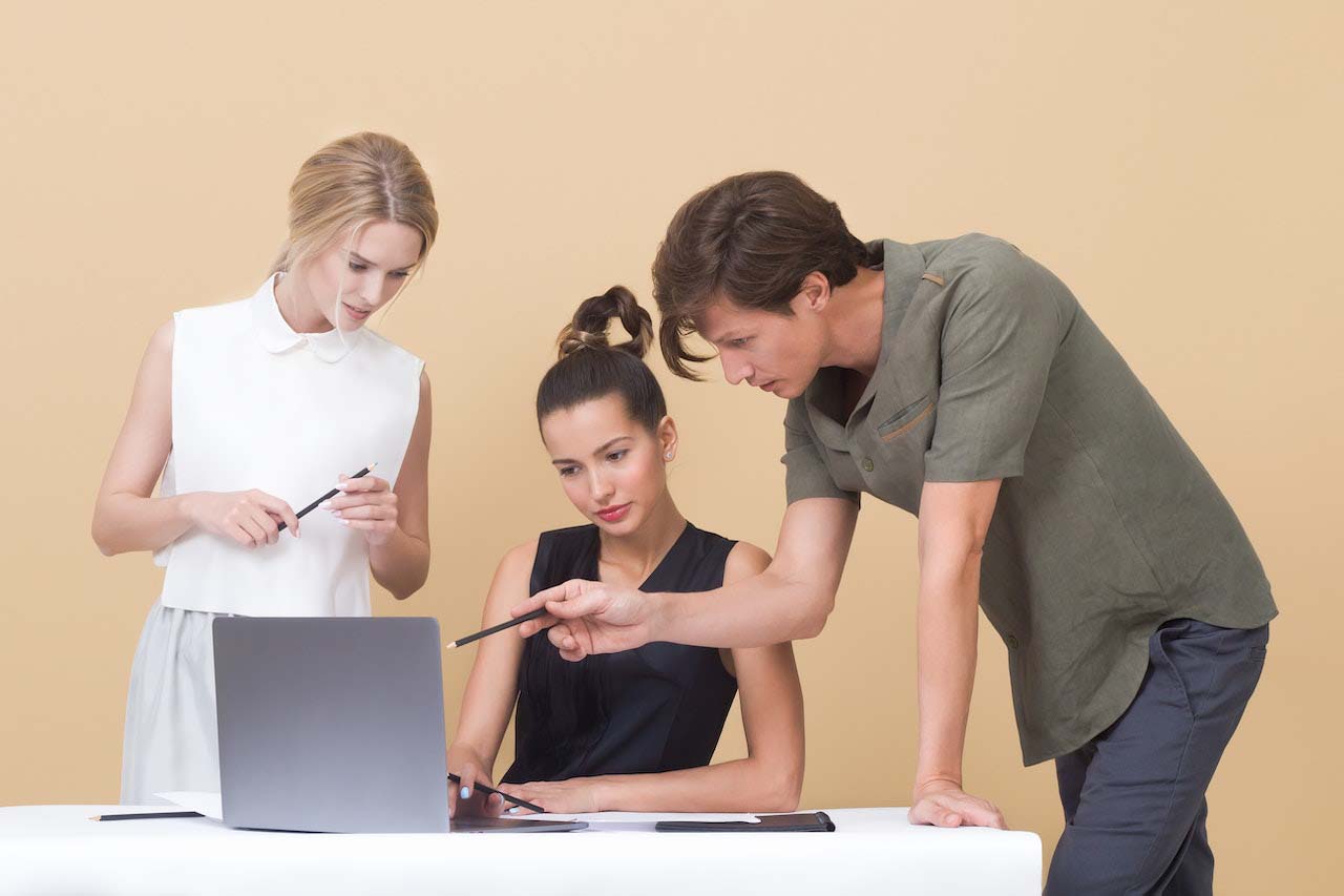 Three young professionals of a digital product development company working together around a laptop