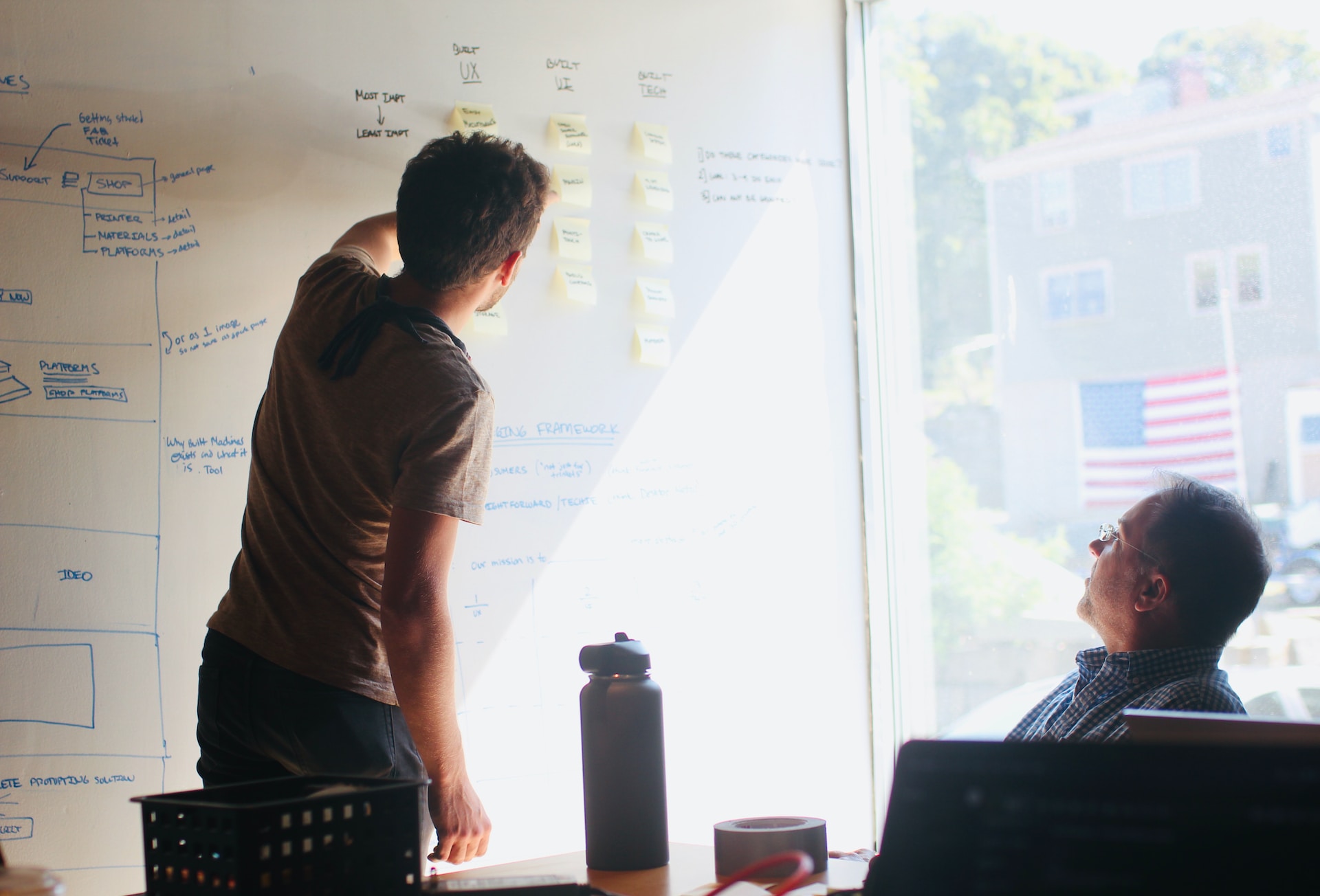 Two young male professionals reviewing logistics of digital product