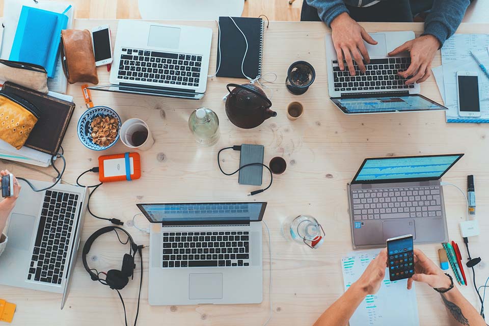 Several employees at a desk using generative AI on their phones and laptops