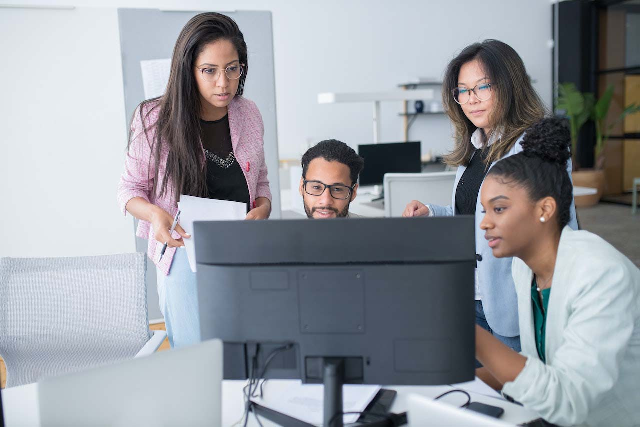 Developer at computer monitor showing stakeholders new features