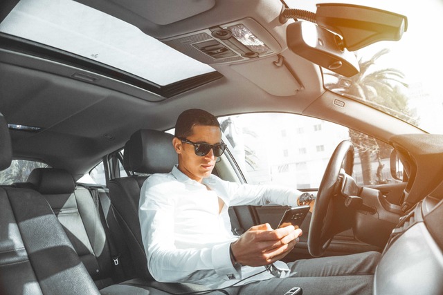 Customer in parked car reviewing data received from his insurance company on his cellphone.